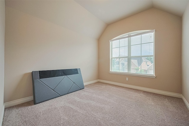 carpeted empty room with baseboards and lofted ceiling