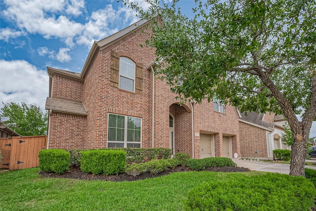 view of front of house with a front yard, driveway, a garage, and brick siding