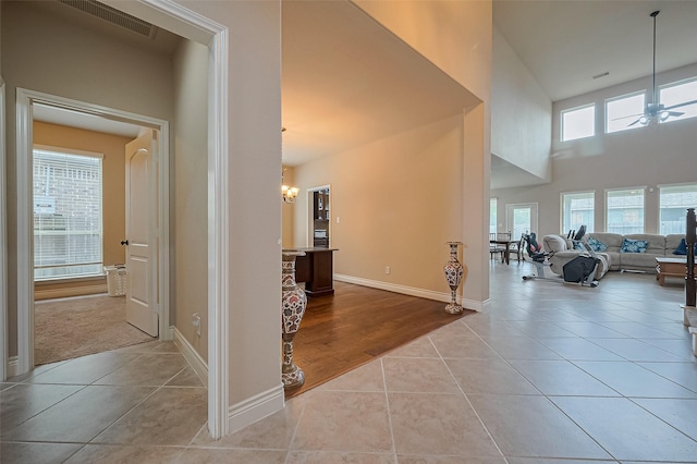 interior space with tile patterned floors, an inviting chandelier, visible vents, and baseboards