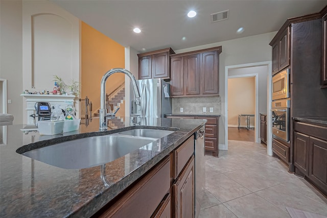 kitchen with dark stone counters, light tile patterned floors, a sink, appliances with stainless steel finishes, and visible vents