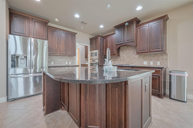 kitchen with dark stone counters, recessed lighting, stainless steel appliances, tasteful backsplash, and visible vents