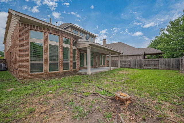 back of house with a fenced backyard, a yard, brick siding, central air condition unit, and a patio area