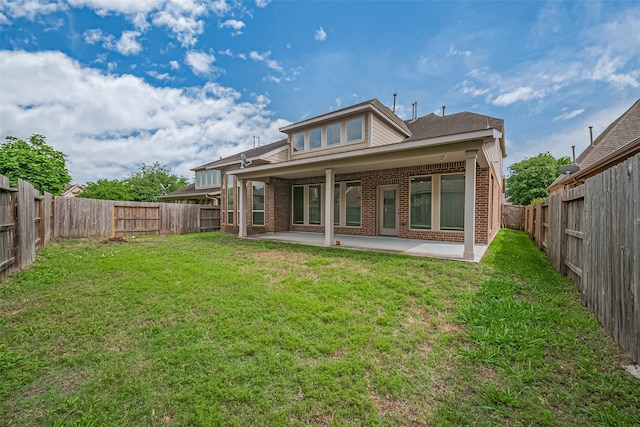 rear view of property with a yard, a patio, brick siding, and a fenced backyard