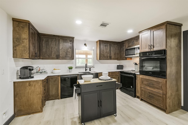 kitchen featuring a sink, visible vents, light countertops, black appliances, and light wood-type flooring