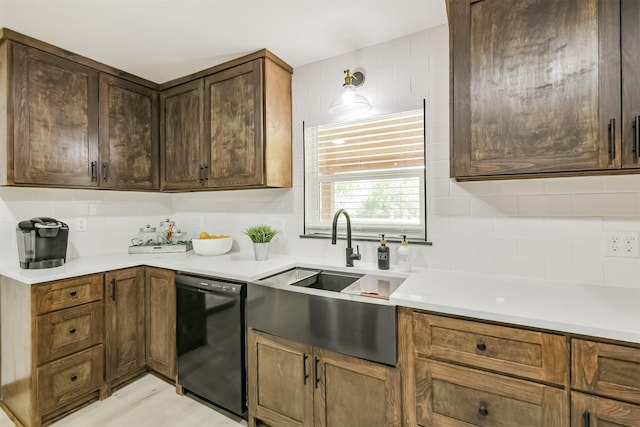 kitchen featuring light countertops, dishwasher, decorative backsplash, and a sink