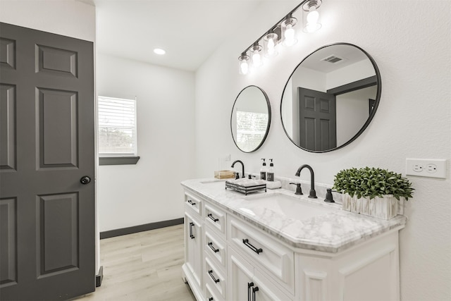 full bath featuring double vanity, wood finished floors, visible vents, and a sink