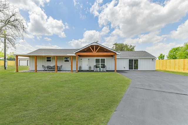 view of front facade with a front lawn, roof with shingles, board and batten siding, and fence