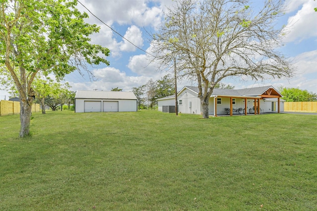 view of yard with an outbuilding, a detached garage, a porch, and fence