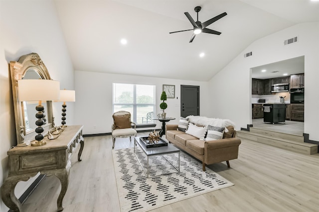 living room featuring ceiling fan, visible vents, light wood-type flooring, and high vaulted ceiling