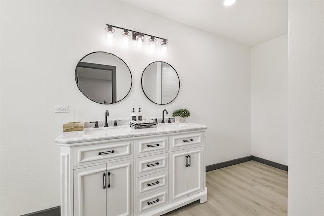 bathroom with double vanity, a sink, wood finished floors, and baseboards