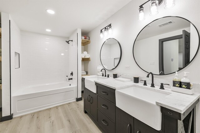 full bath featuring double vanity, wood finished floors, visible vents, and a sink