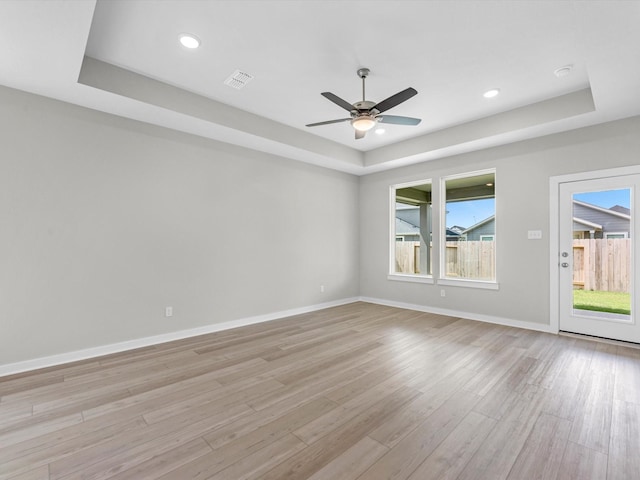21703 White Bellflower Ln, Cypress, TX 77433 - empty room with a raised ceiling, light wood-style flooring, a ceiling fan, healthy amount of natural light, and recessed lighting