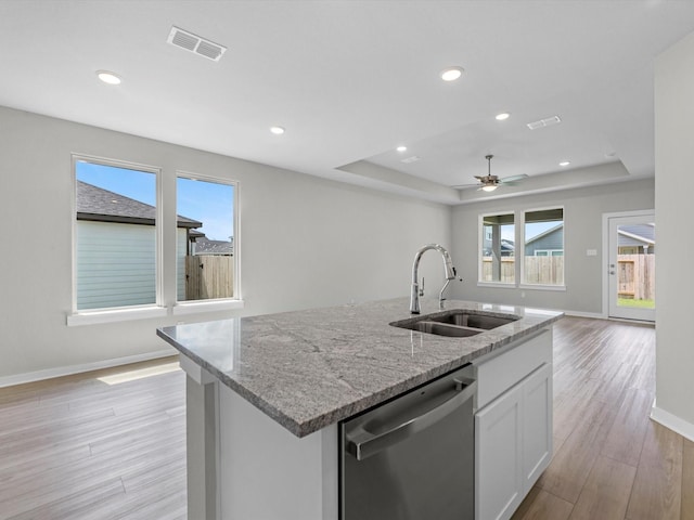 21703 White Bellflower Ln, Cypress, TX 77433 - kitchen featuring stainless steel dishwasher, light wood finished floors, open floor plan, an island with sink, and white cabinets