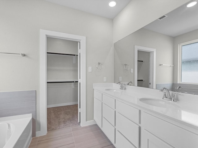21703 White Bellflower Ln, Cypress, TX 77433 - bathroom with double vanity, a spacious closet, a bath, and recessed lighting