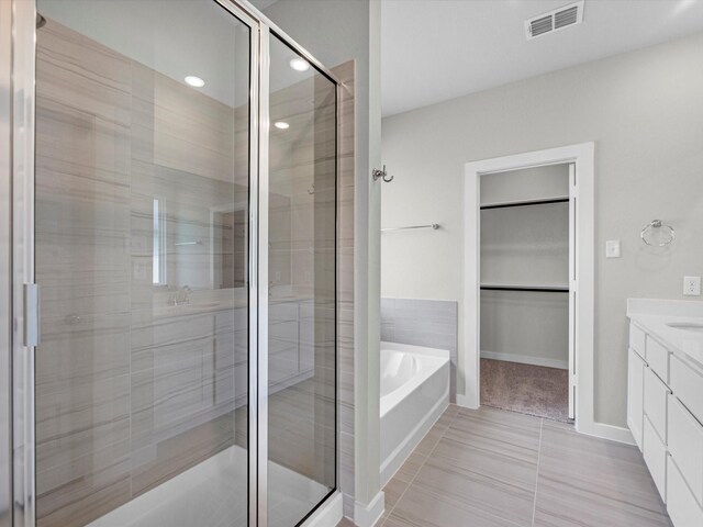 21703 White Bellflower Ln, Cypress, TX 77433 - bathroom featuring a shower stall, vanity, a garden tub, a spacious closet, and tile patterned floors