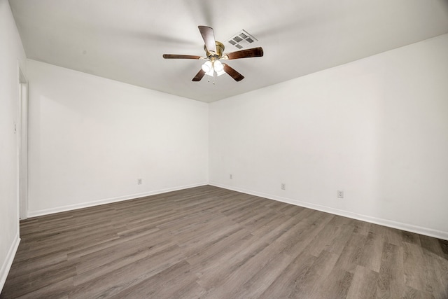 unfurnished room featuring dark wood finished floors, visible vents, ceiling fan, and baseboards