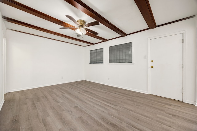 spare room with beamed ceiling, a ceiling fan, baseboards, and light wood-type flooring