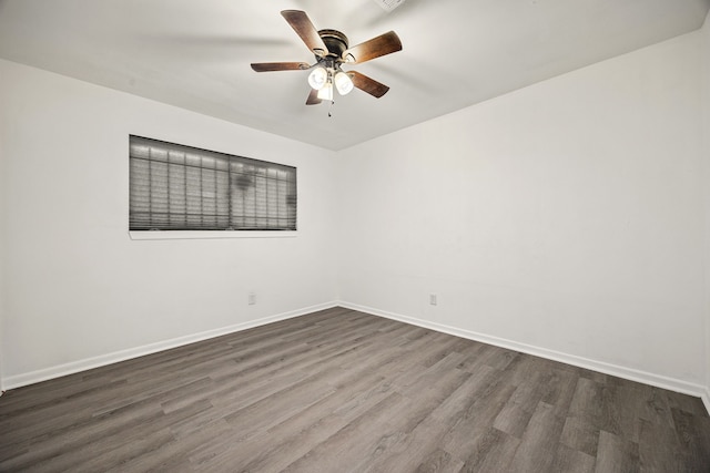 unfurnished room featuring dark wood-style floors, a ceiling fan, and baseboards