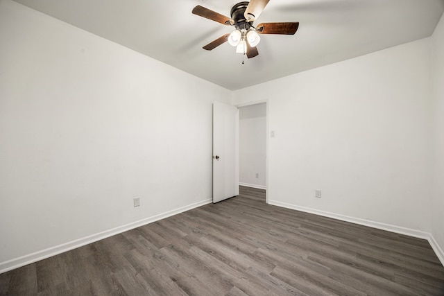 spare room featuring a ceiling fan, dark wood finished floors, and baseboards