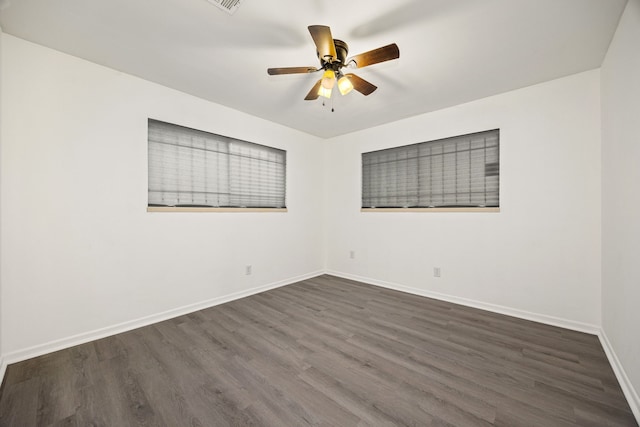 empty room featuring a ceiling fan, dark wood-style flooring, and baseboards