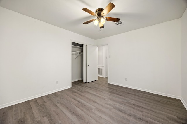 unfurnished bedroom with dark wood-style floors, a closet, visible vents, and baseboards