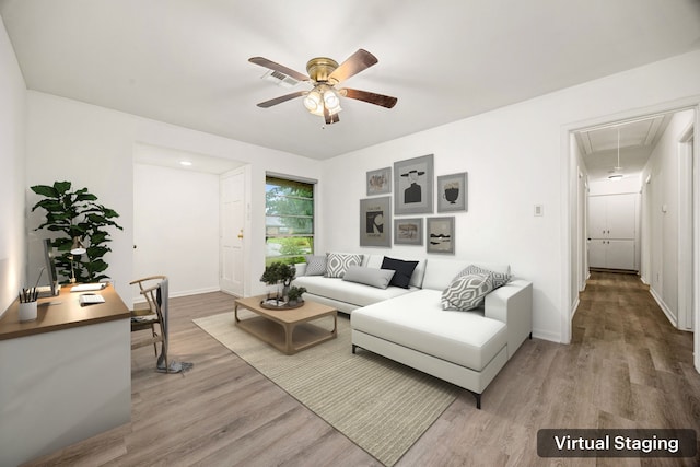 living room featuring light wood-style flooring, attic access, ceiling fan, baseboards, and visible vents