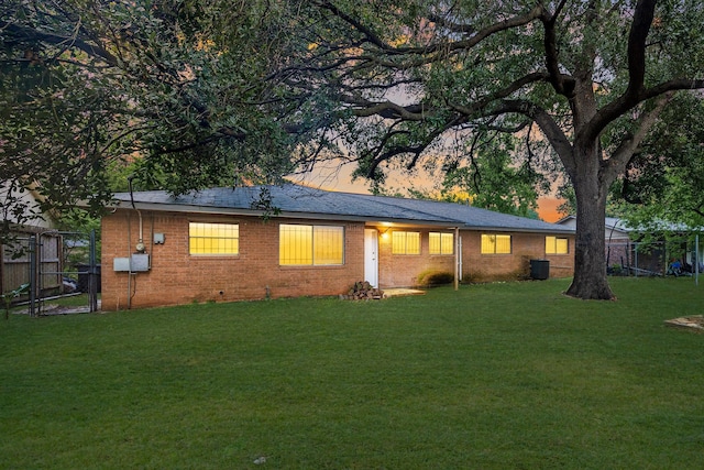 rear view of house featuring a gate, cooling unit, a lawn, brick siding, and fence
