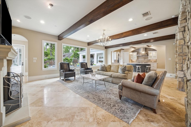 living room with an inviting chandelier, visible vents, beamed ceiling, baseboards, and arched walkways