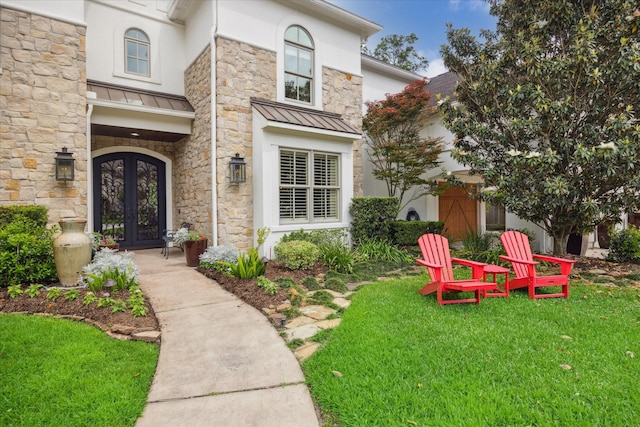 doorway to property with french doors, a yard, a standing seam roof, and stone siding