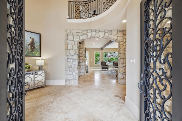 entrance foyer with arched walkways, baseboards, decorative columns, and a high ceiling