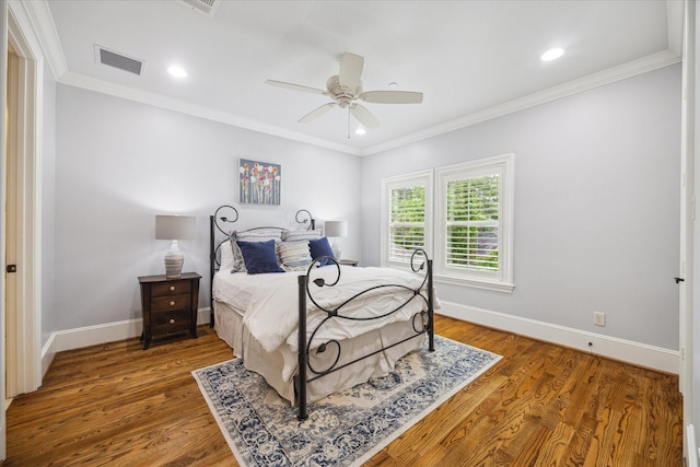 bedroom with baseboards, visible vents, ornamental molding, and wood finished floors
