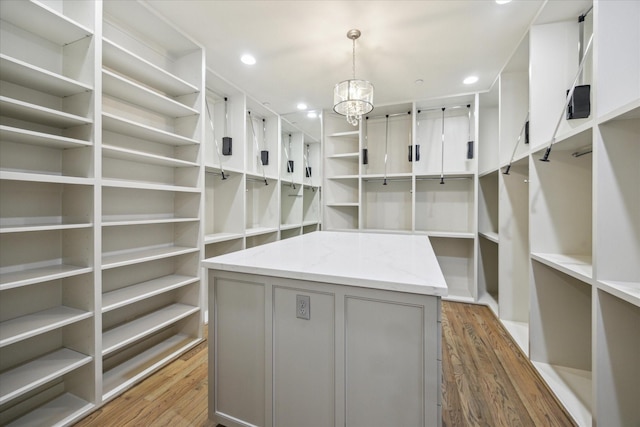 spacious closet with an inviting chandelier and wood finished floors
