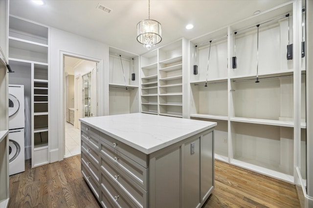 spacious closet with stacked washing maching and dryer, dark wood-style floors, a chandelier, and visible vents