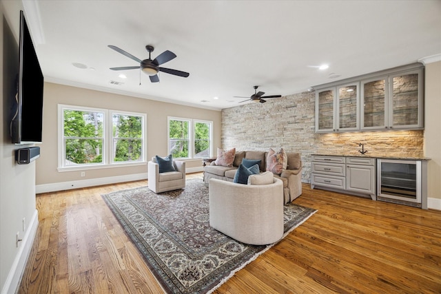 living room with wine cooler, ceiling fan, wet bar, and wood finished floors