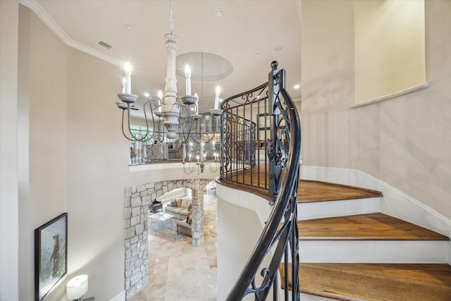 stairway with a notable chandelier, ornamental molding, and visible vents