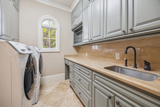 laundry area with washing machine and clothes dryer, cabinet space, a sink, baseboards, and ornamental molding