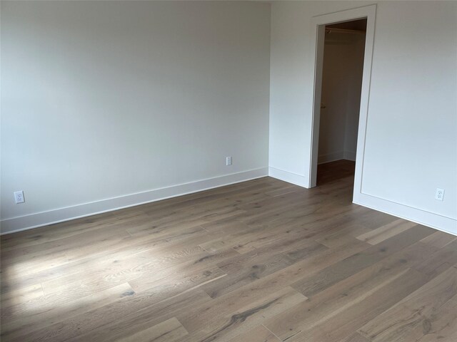 spare room with baseboards and dark wood-type flooring