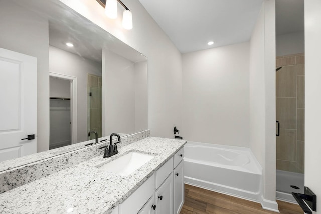 full bathroom with wood finished floors, a shower stall, a bath, and vanity