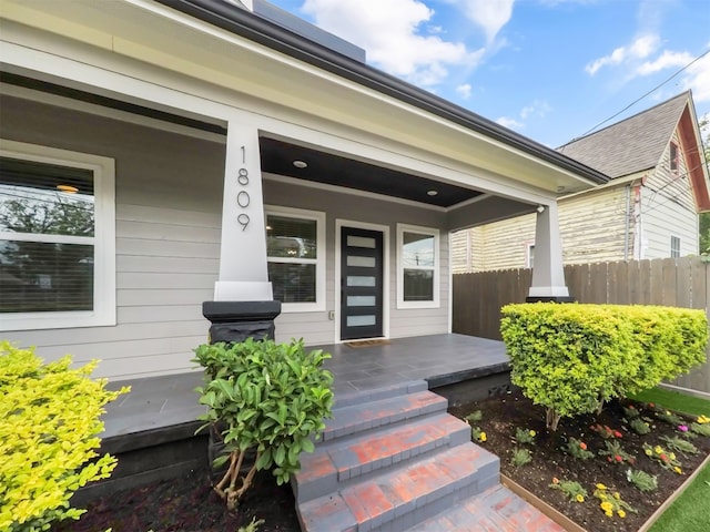 doorway to property with fence and covered porch