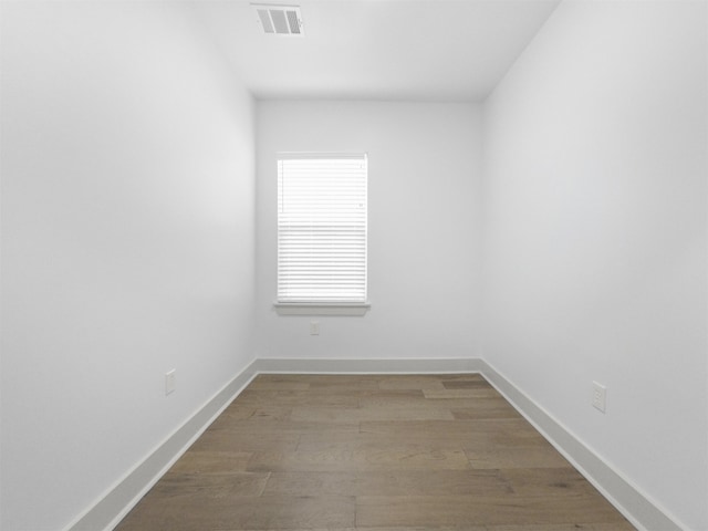 unfurnished room featuring visible vents, wood finished floors, and baseboards