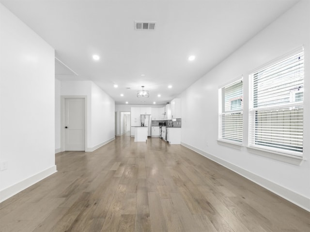 unfurnished living room with recessed lighting, visible vents, light wood-style flooring, and baseboards