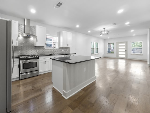 kitchen featuring dark countertops, visible vents, appliances with stainless steel finishes, and wall chimney range hood