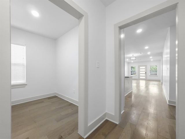 hall featuring baseboards, recessed lighting, and wood finished floors