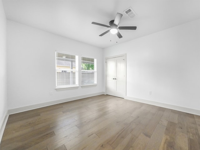 spare room with baseboards, visible vents, wood finished floors, and ceiling fan
