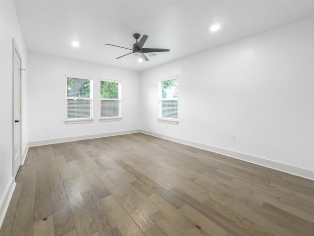 spare room featuring wood-type flooring, recessed lighting, ceiling fan, and baseboards