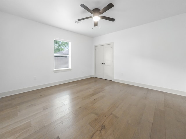 spare room featuring baseboards, visible vents, ceiling fan, and light wood finished floors