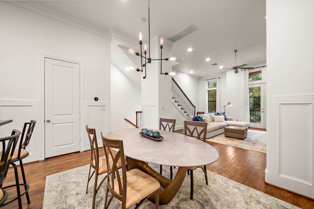 dining room with ceiling fan, wood finished floors, stairway, and a decorative wall