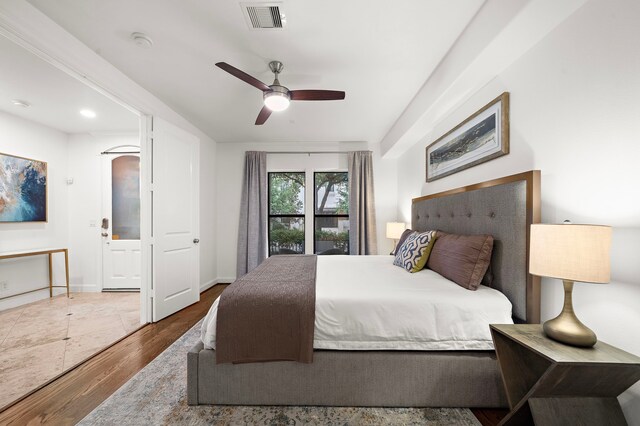 bedroom with a ceiling fan, visible vents, and wood finished floors