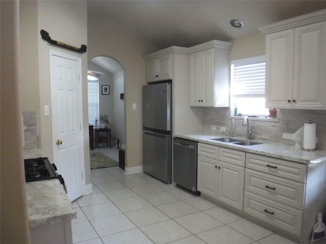kitchen featuring a sink, tasteful backsplash, dishwashing machine, white cabinets, and freestanding refrigerator