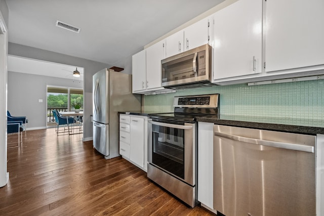 kitchen with appliances with stainless steel finishes, dark wood-type flooring, dark countertops, and white cabinetry
